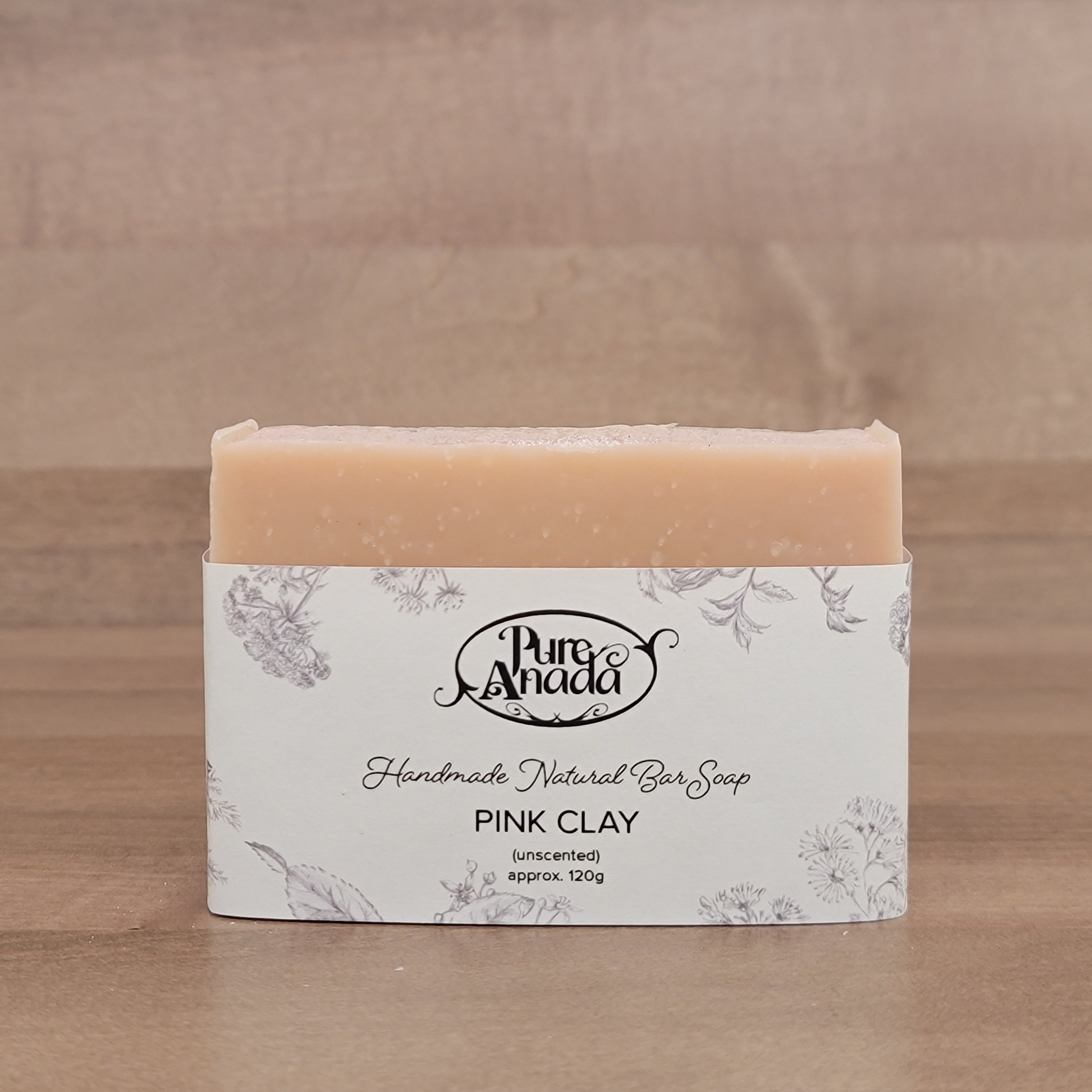 Bar of handmade unscented natural soap with packaging on a wooden surface